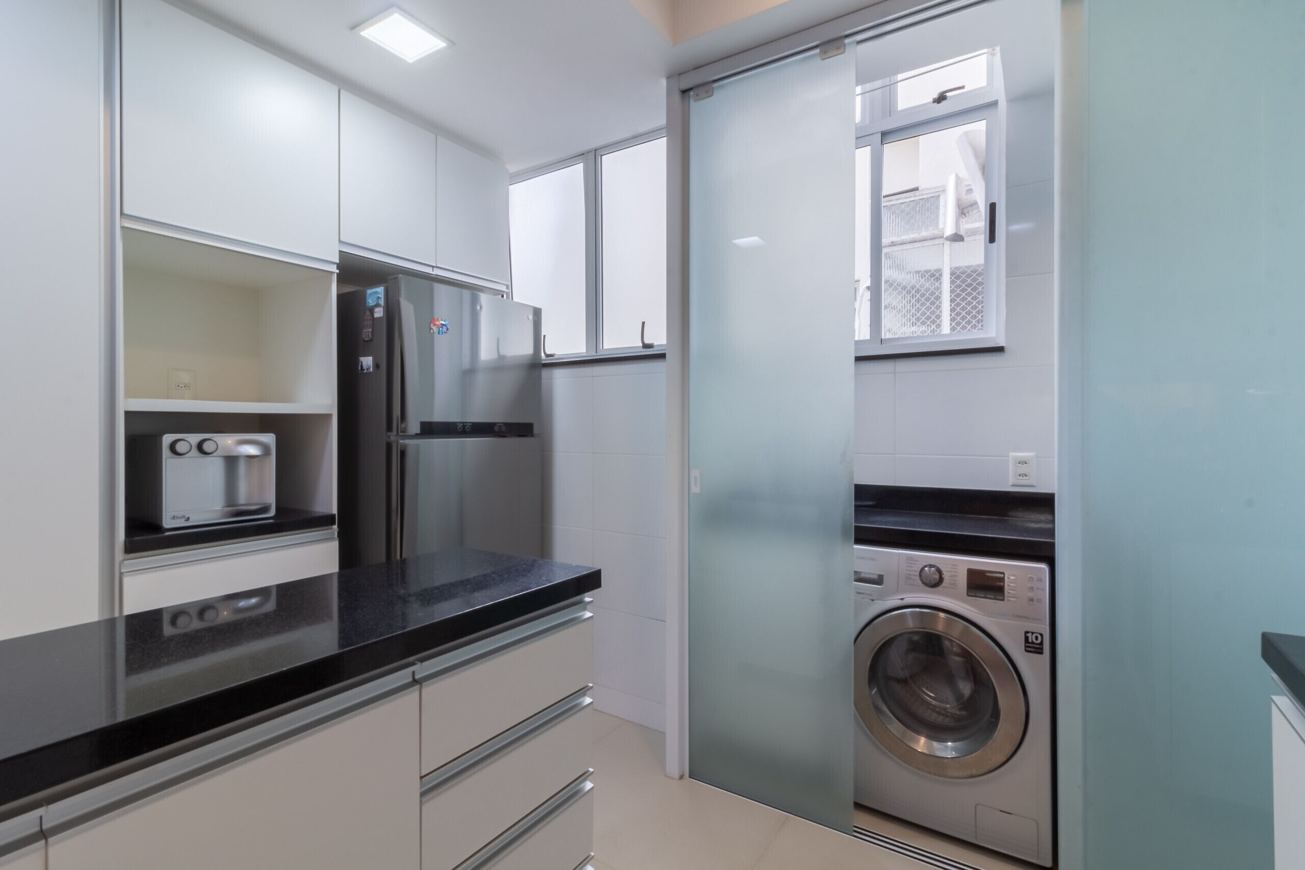 A compact kitchen with a built-in washing machine, a toaster, and a refrigerator.