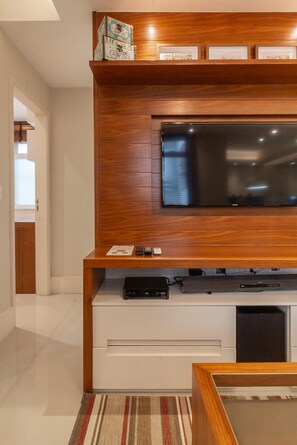 A modern living room with a wooden entertainment unit, a flat-screen TV, and a small table. - 8 minutes from Ipanema beach | NS204 (Rio de Janeiro)