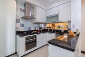 Een moderne keuken met witte kasten, een roestvrijstalen fornuis en een zwart aanrecht.
