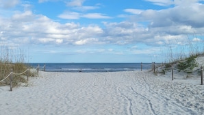En sandstrand med fri utsikt över havet och ett fartyg i fjärran.