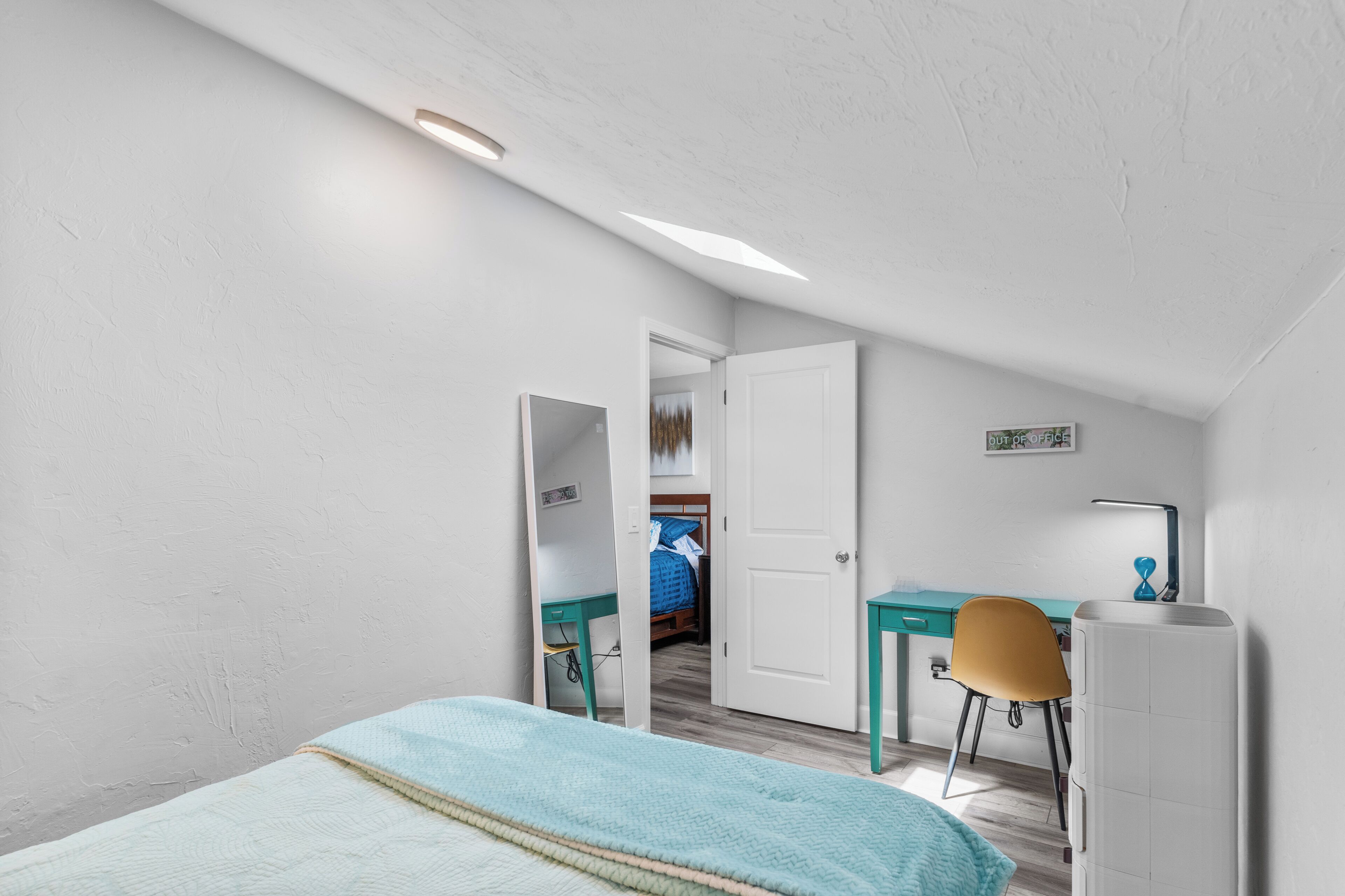 Un dormitorio con cama, escritorio, silla y armario.