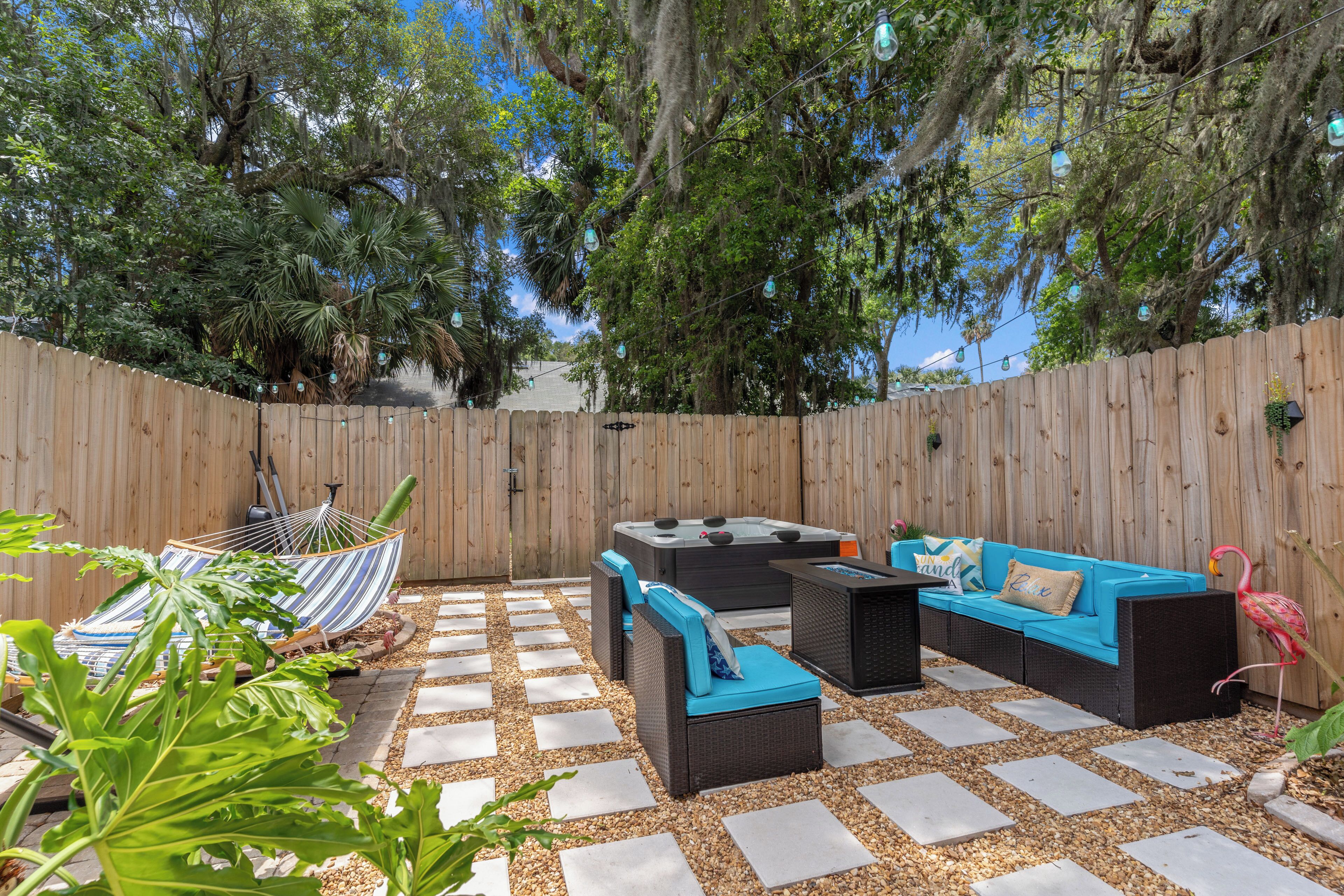 A backyard with a wooden fence, outdoor furniture, and a hammock.