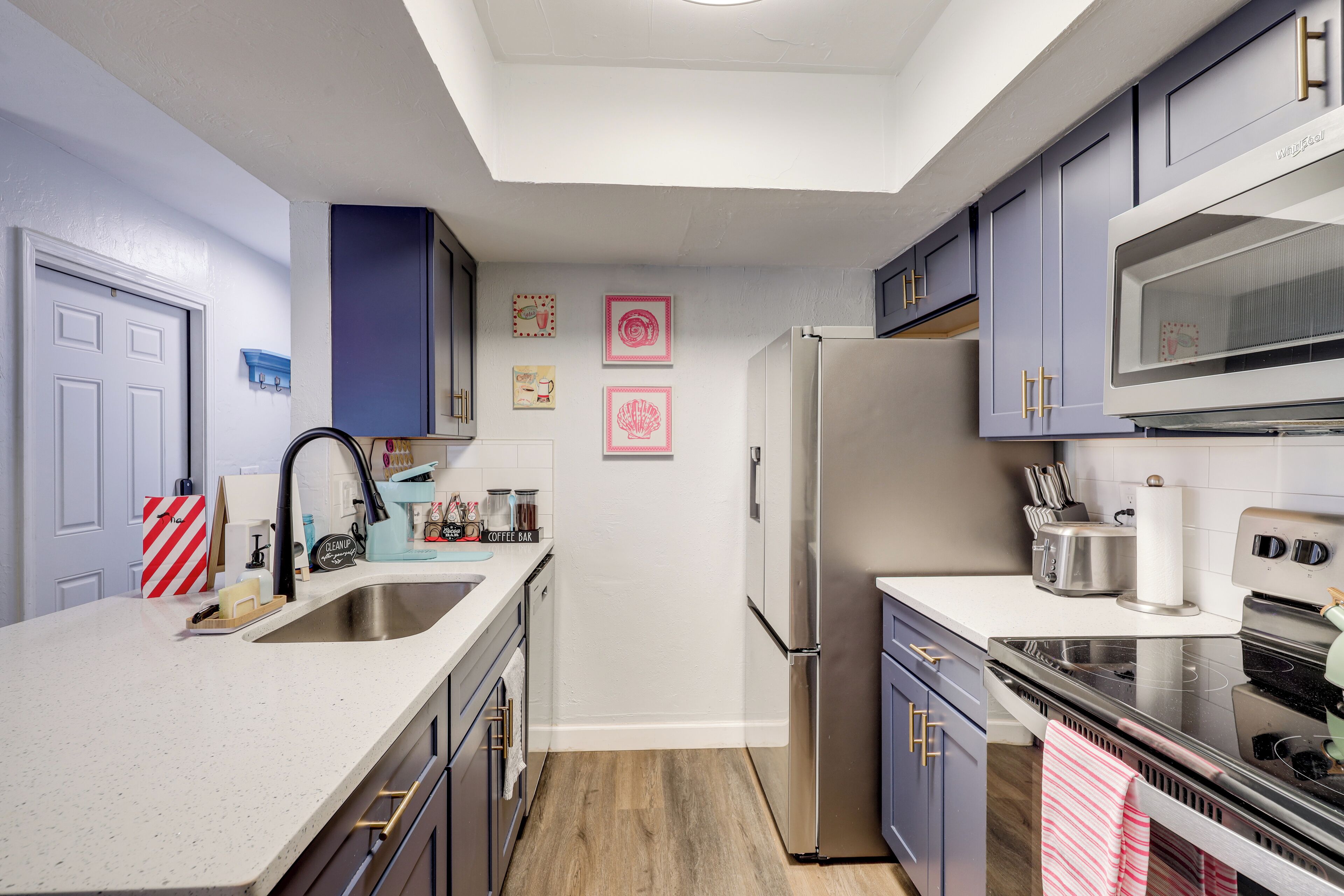 A modern kitchen with a central island, stainless steel appliances, and blue cabinetry.