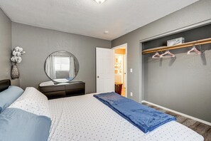 A bedroom with a bed, dresser, mirror, and a closet with hangers. - Easily Explore Anchorage! Modern Duplex Near Town (Anchorage)