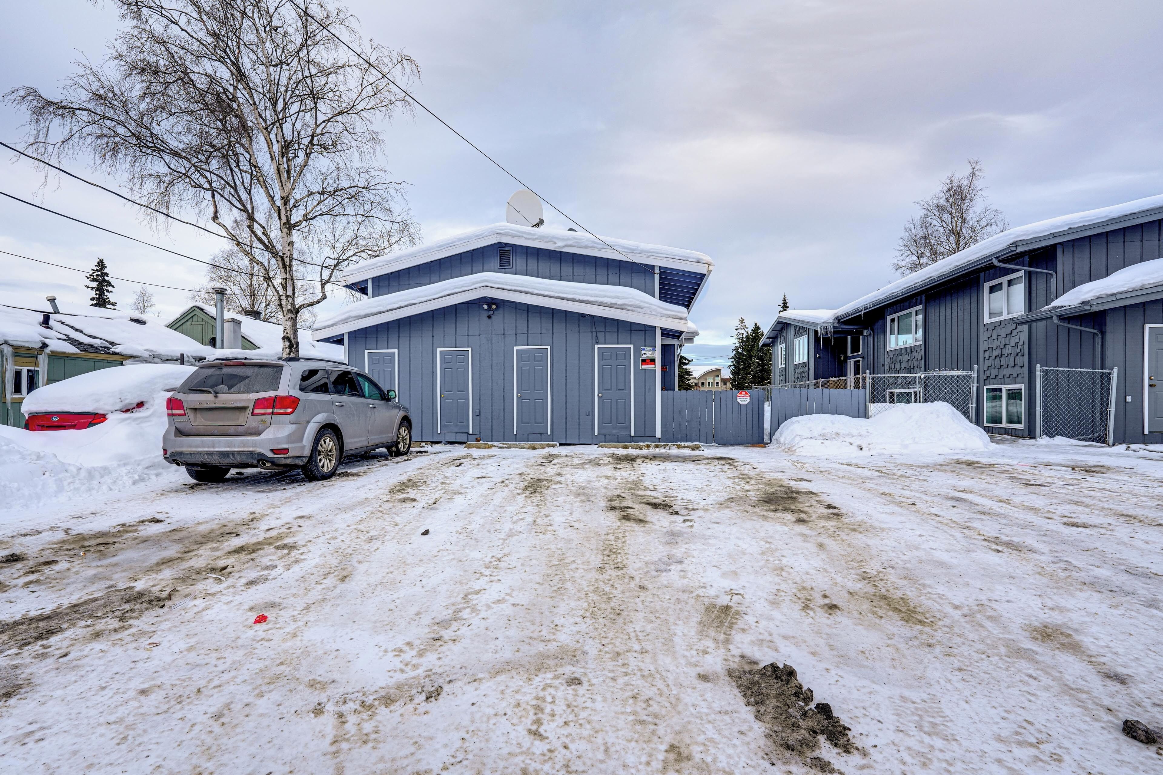 A residential area with a snow-covered driveway and houses.