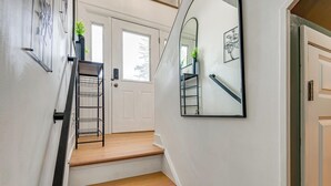 Un escalier avec une étagère en métal, une porte avec une fenêtre et un miroir au mur.
