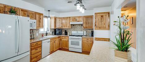 A kitchen with wooden cabinets, a white refrigerator, a stove, and a microwave.