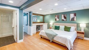 Une chambre à coucher avec un lit, des tables de chevet, un bureau et un miroir.