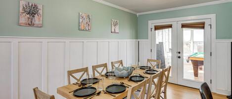 Comedor con una mesa de madera dispuesta para seis personas, rodeada de seis sillas.