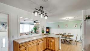 Une cuisine avec des meubles de rangement en bois, un plan de travail et un coin repas comprenant des chaises et une table.