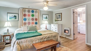 Une chambre à coucher comprenant un lit, un ventilateur de plafond, un radiateur, un banc en bois et une courtepointe.