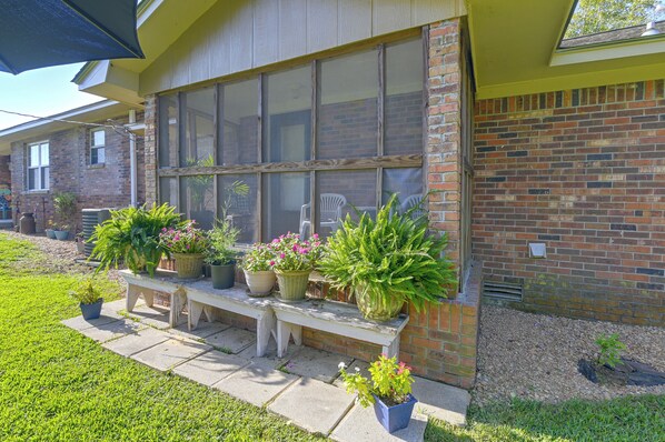 A building with a large window, a bench, and potted plants. - Noxapater Fall Retreat for Hunting & MSU Games (Noxapater)