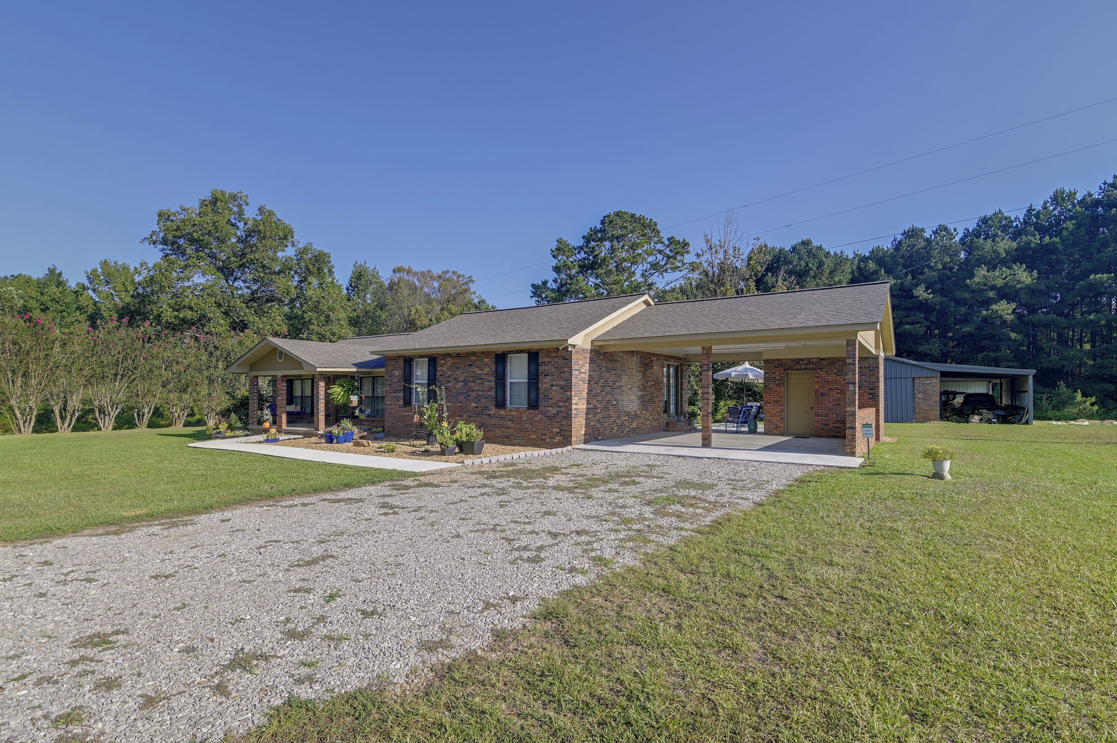 A two-story brick house with a covered porch and a gravel driveway.