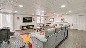Een ruime woonkamer met een bank, een pooltafel en een televisie.