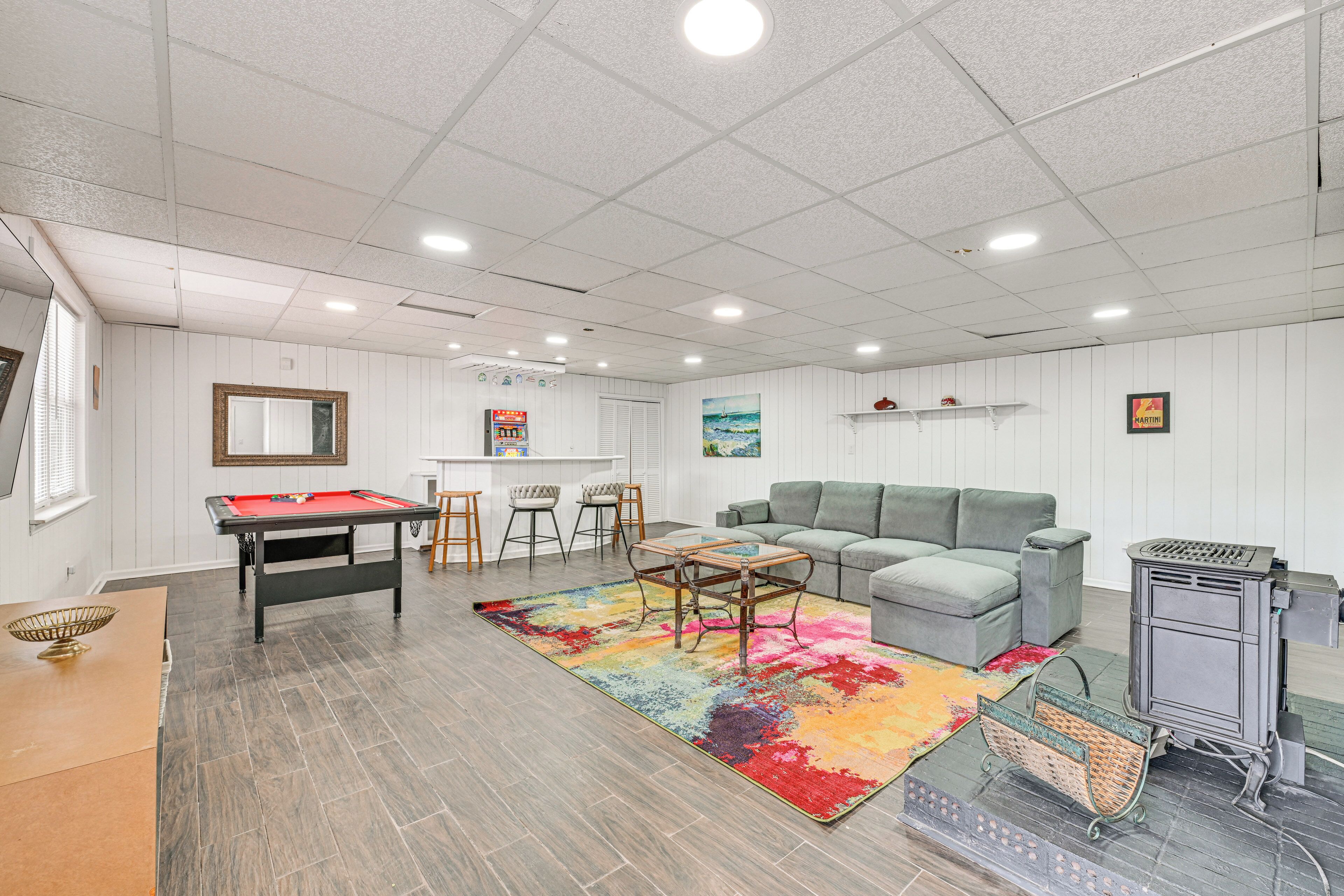 Una sala de estar con mesa de billar, una alfombra colorida, un sofá y una chimenea.