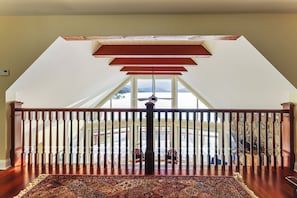 A spacious room with a wooden floor, a large window, and a view of a snowy landscape. - Year-round Fun in Putnam Station: Lakefront Home! (Town of Putnam)