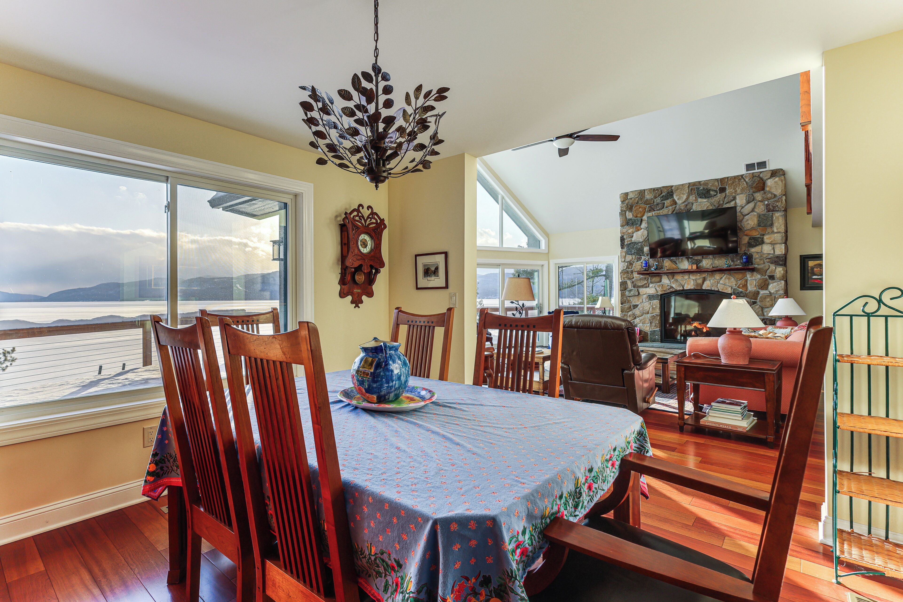 A dining area with a table set for four, a fireplace, and a view of the ocean.