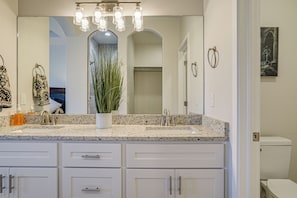 Une salle de bain avec un meuble-lavabo à deux vasques, un grand miroir et une plante en pot.