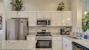 A modern kitchen with white cabinets, stainless steel appliances, granite countertops, and a dishwasher. - Mountain-view Retreat Near Organ Wilderness Trails (Las Cruces)