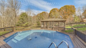 A rectangular swimming pool with a wooden deck and metal railings, surrounded by trees and a gazebo. - Beautiful & Unique Farmhouse 15 Mi to Saratoga (Fort Edward)