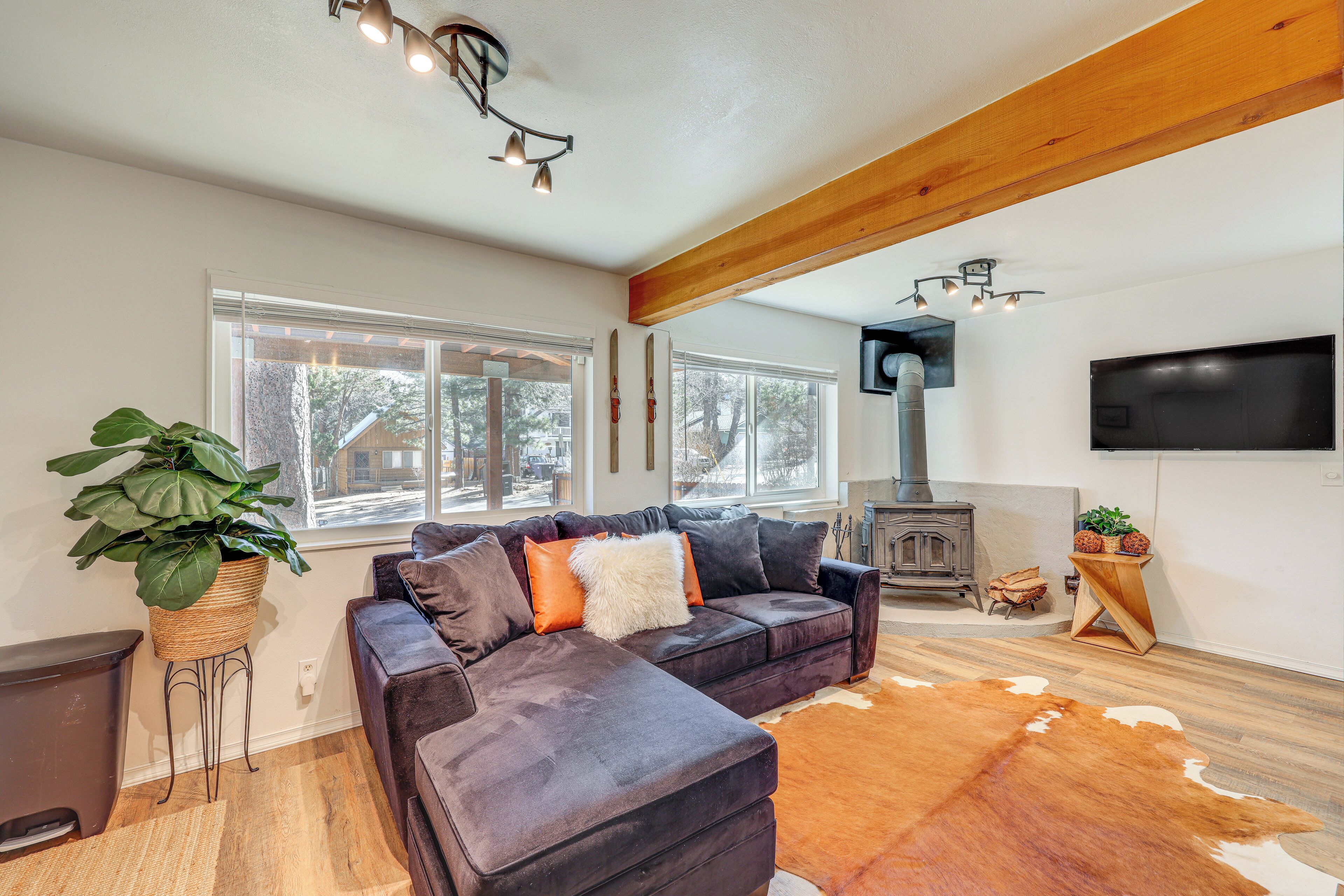 Una sala de estar moderna con un sofá modular, un ventanal grande, una chimenea y un televisor montado.