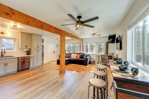 A spacious kitchen with wooden beams, a dining area with bar stools, a large window, and a cozy seating area with a fireplace. - 5 Mi to Lake & Skiing! All-season Big Bear Base (Sugarloaf)