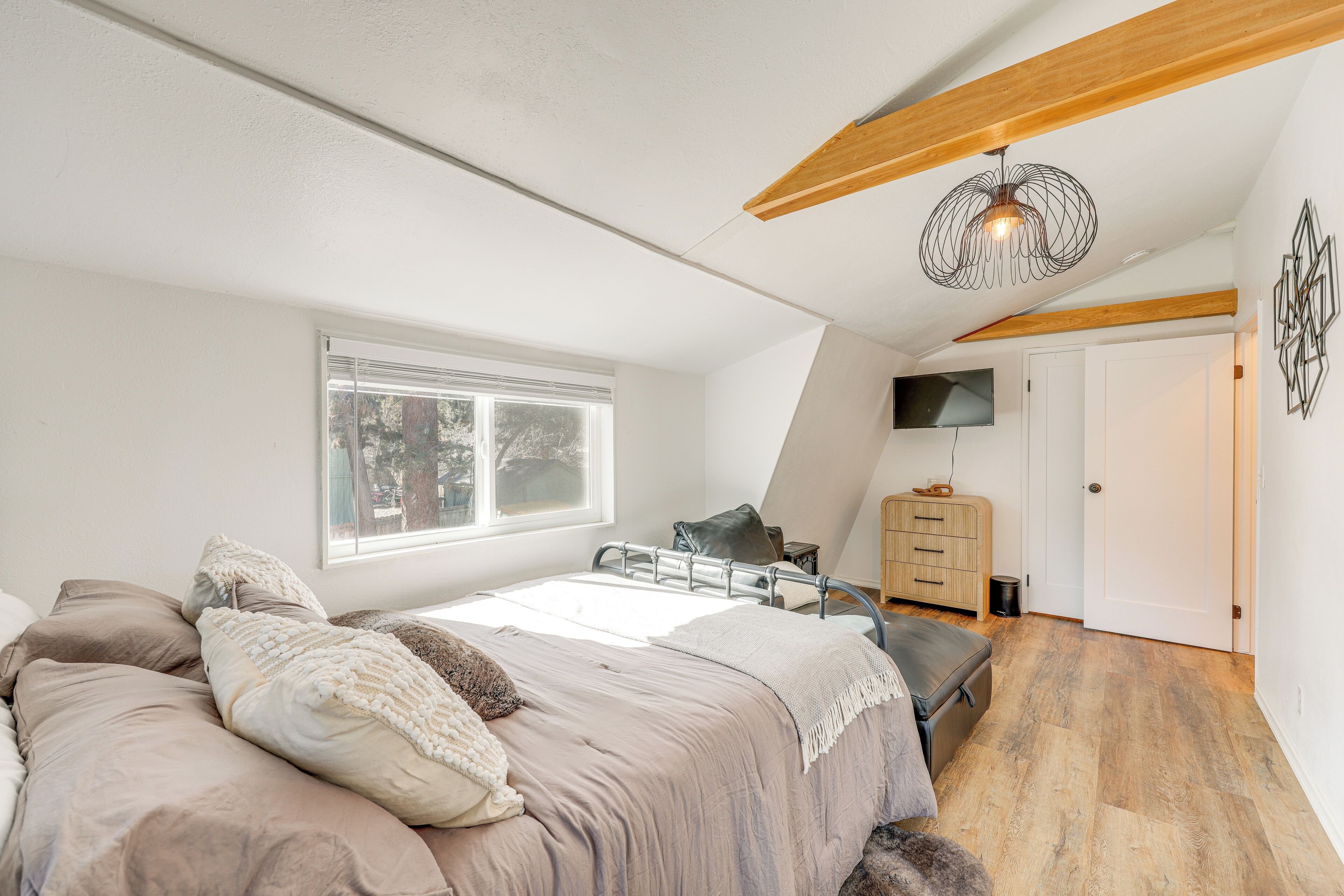 A bedroom with a bed, a dresser, a television, and a window.