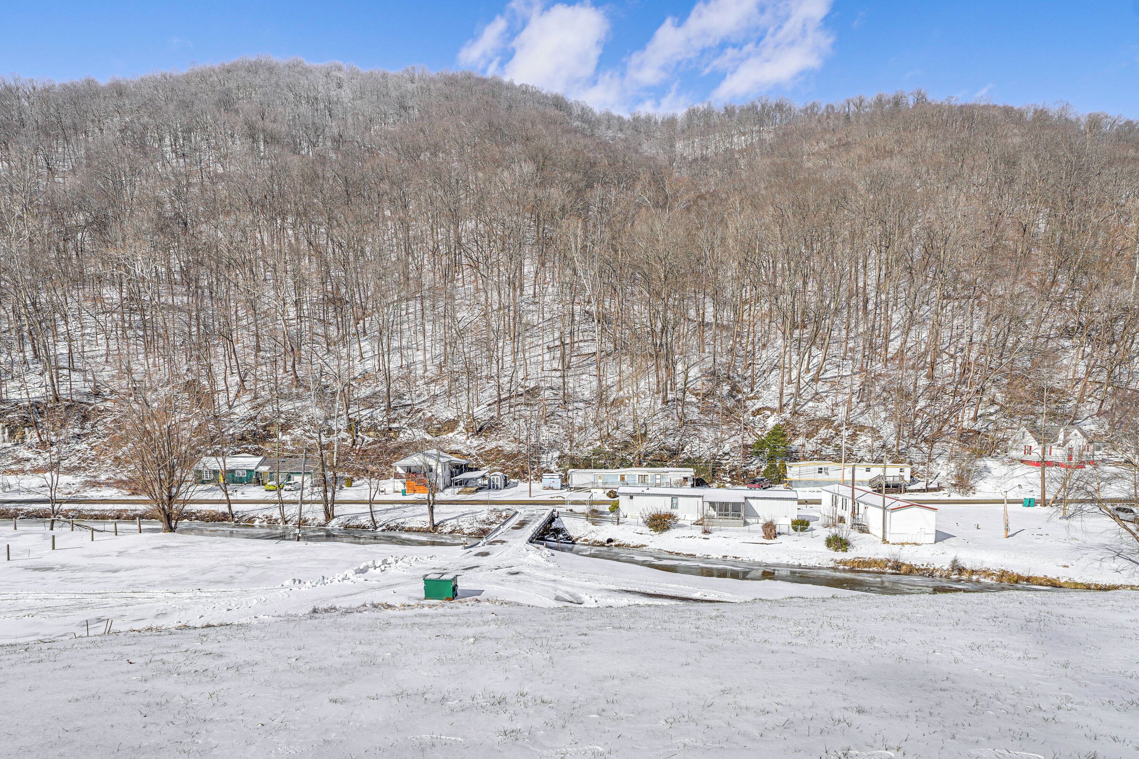 A snow-covered landscape with a small cluster of buildings, a road, and a river.