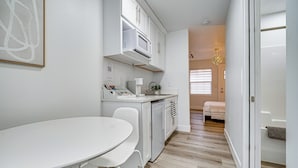 A compact kitchen with white cabinetry, a microwave, and a dishwasher. There is a small dining area with a white table and chairs. - Walk to Main Ave & Soap Lake! Pet-friendly Studio (Soap Lake)