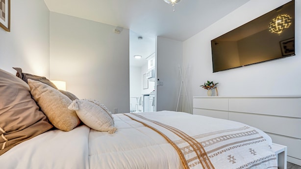A modern bedroom with a large bed, a bedside table, and a mounted TV. - Walk to Main Ave & Soap Lake! Pet-friendly Studio (Soap Lake)