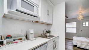 A modern kitchen with white cabinets, a built-in microwave, a coffee maker, and a dishwasher. - Walk to Main Ave & Soap Lake! Pet-friendly Studio (Soap Lake)