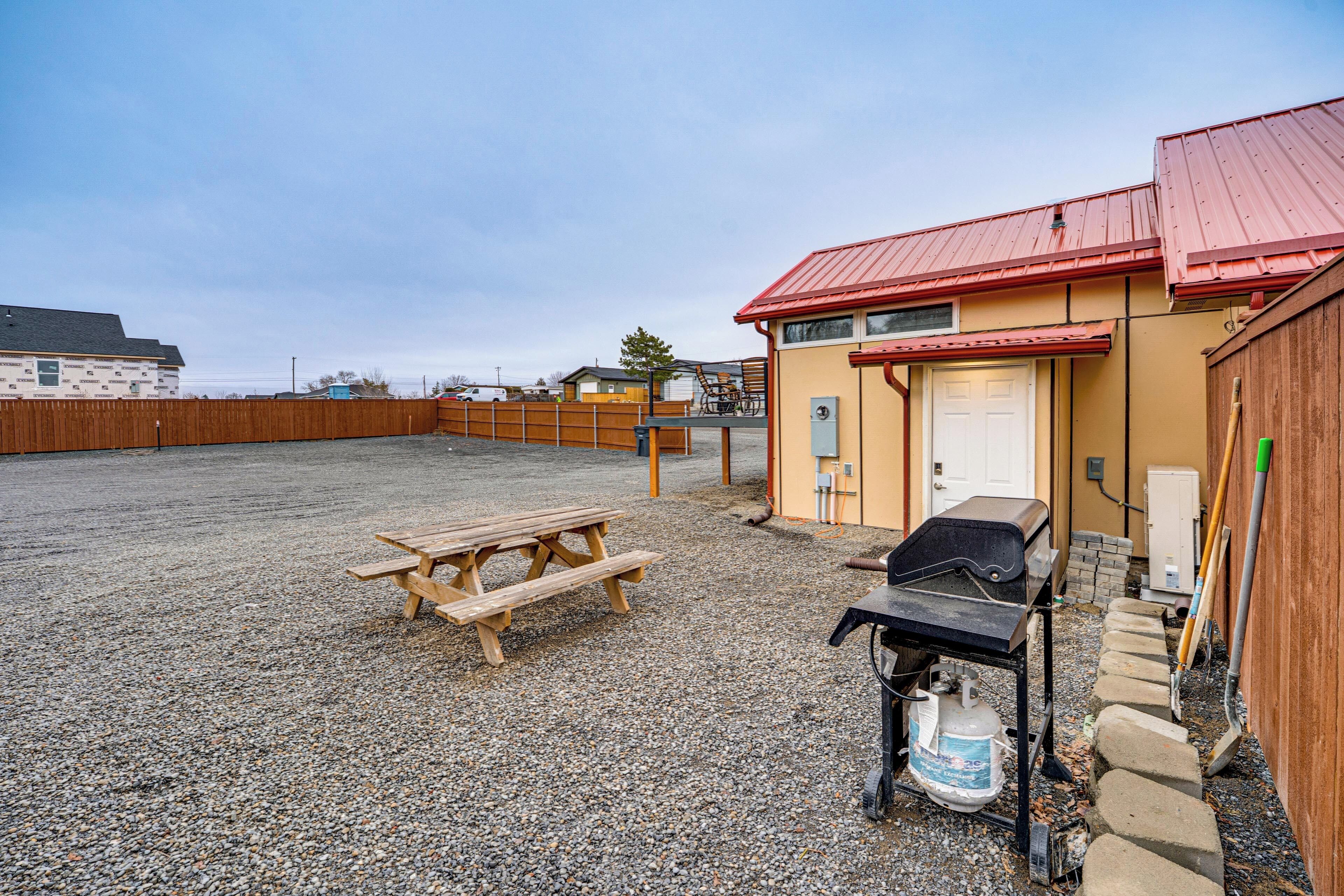 Un patio de grava con una mesa de picnic y una parrilla.
