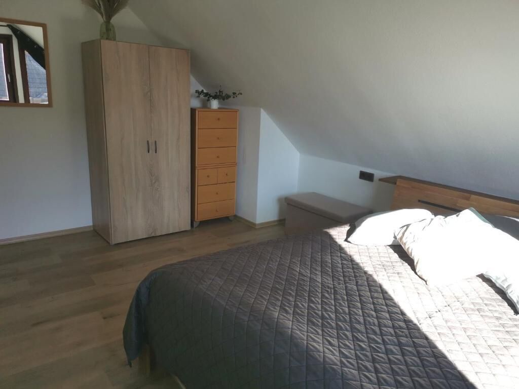 Een slaapkamer met een bed, een kledingkast, een dressoir en een bankje.