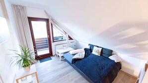 Een slaapkamer met een bed, een nachtkastje, een potplant en een raam.