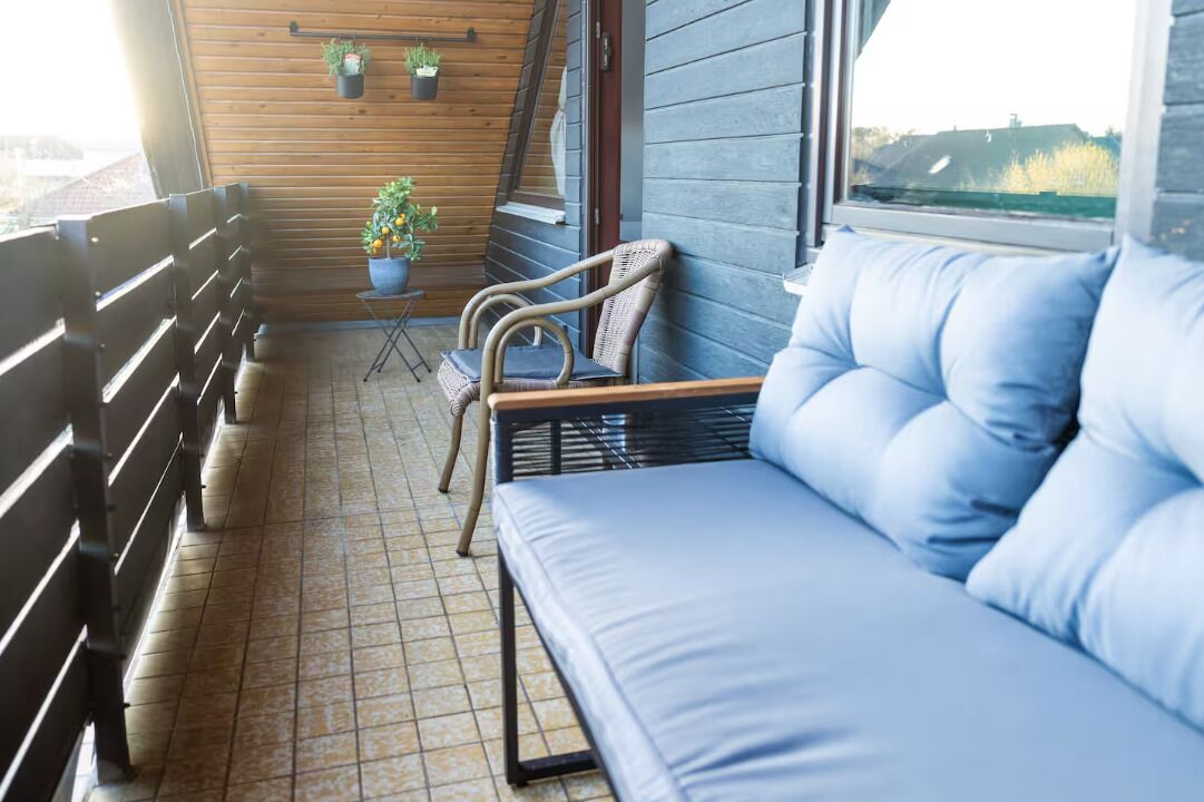 Un balcon avec un canapé, des chaises et des plantes en pot.