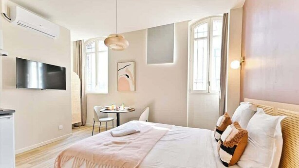 Ein modernes Hotelzimmer mit einem Bett, einem Flachbildfernseher, einem Essbereich und einem großen Fenster.