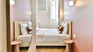 Ein Zimmer mit Spiegel, Bett, zwei Nachttischen und Fenster.