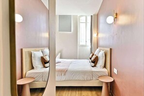 Ein Zimmer mit Spiegel, Bett, zwei Nachttischen und Fenster.