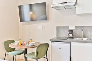 A modern kitchen with a flat-screen TV, a built-in oven, and a dishwasher. - Studio 15m² avec clim – Pratique et fonctionnel (Le Pré-Saint-Gervais)
