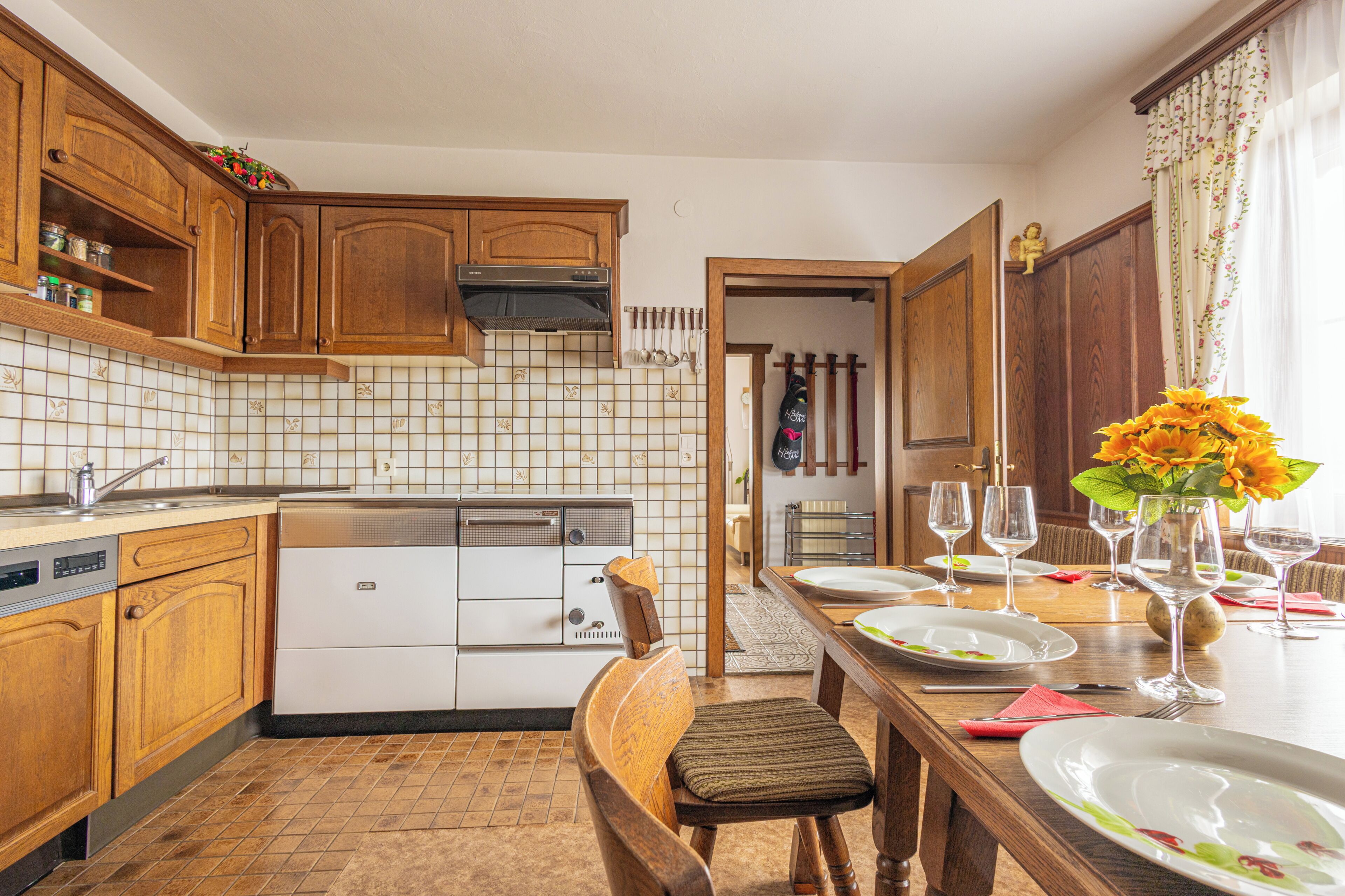 A kitchen with wooden cabinets, a dishwasher, and a dining table set for a meal.