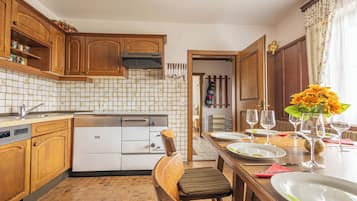 A kitchen with wooden cabinets, a dishwasher, and a dining table set for a meal.