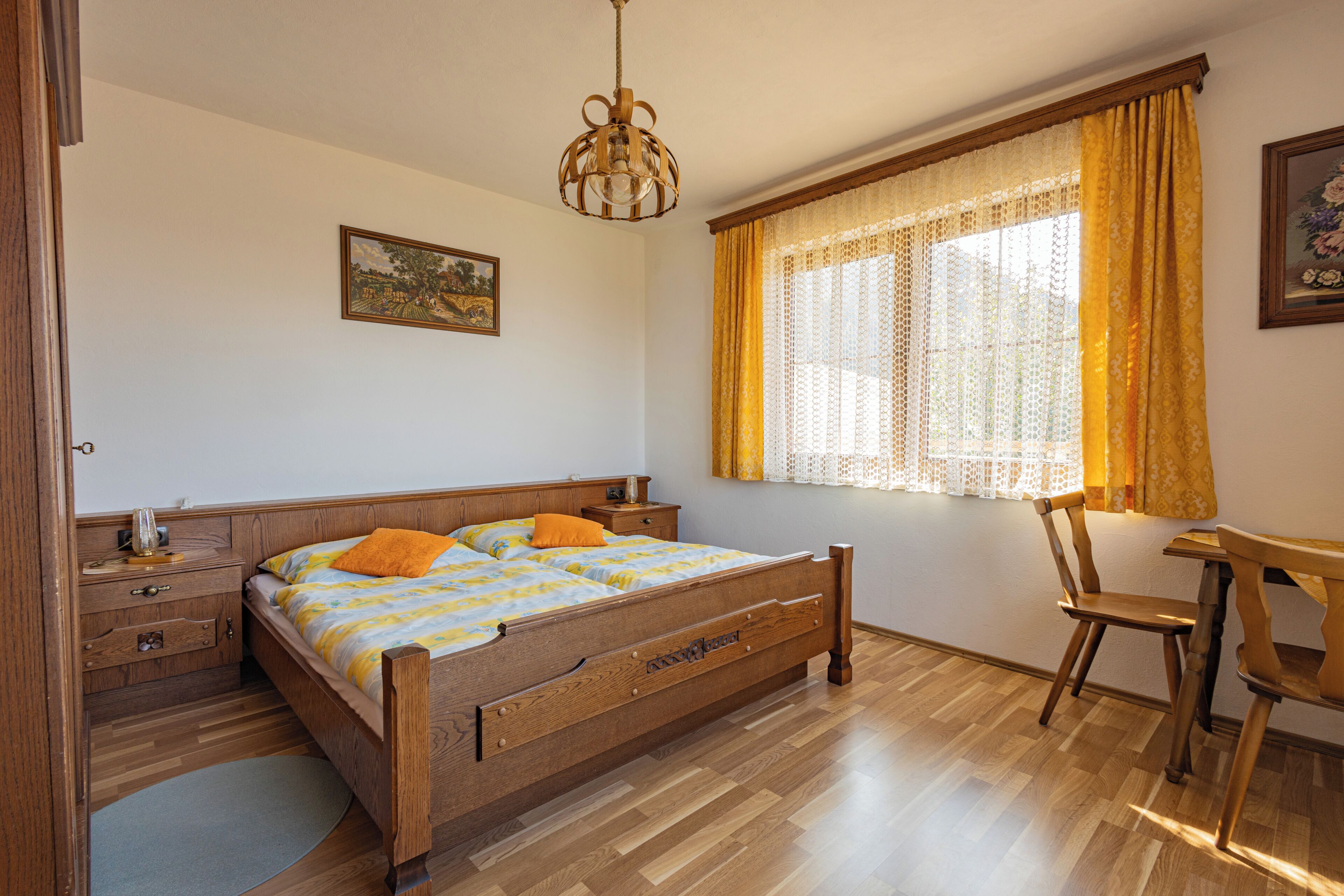 A bedroom with a wooden bed, a nightstand, a desk, and a chair.