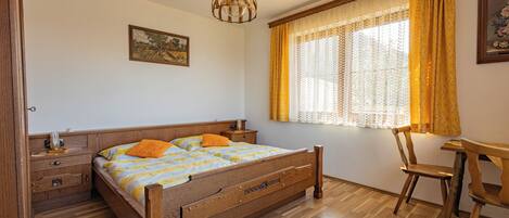 A bedroom with a wooden bed, a nightstand, a desk, and a chair.