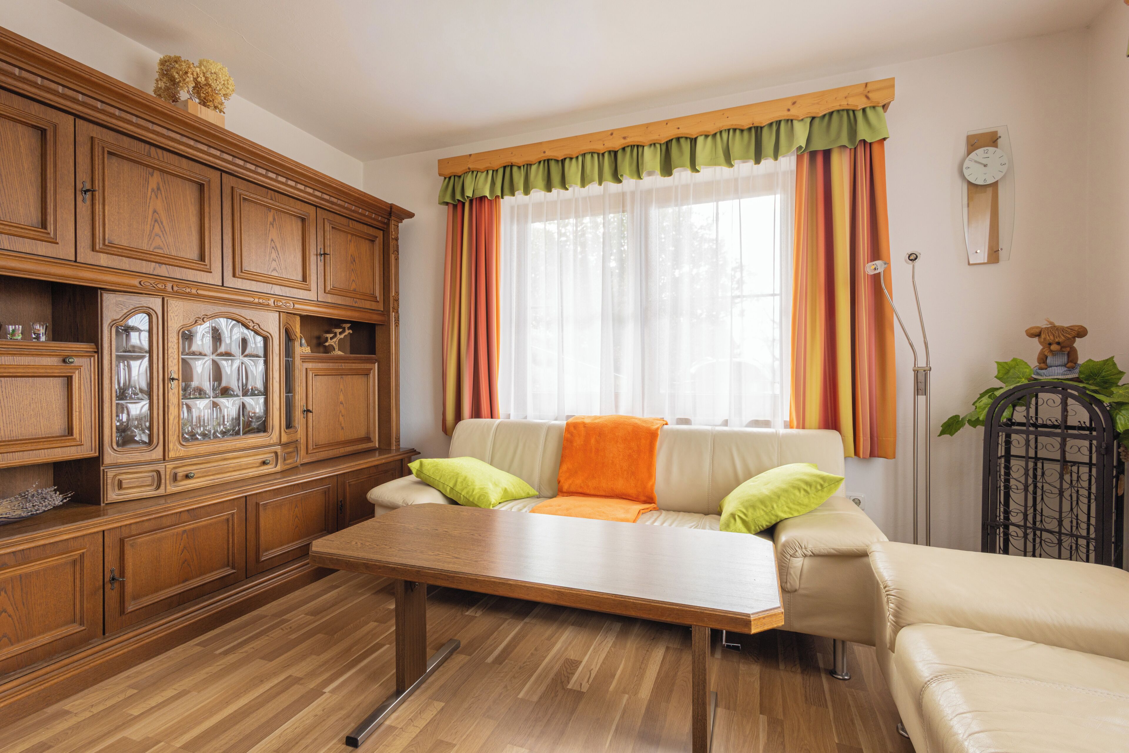A living room with a wooden cabinet, a sofa, a coffee table, and a window with curtains.