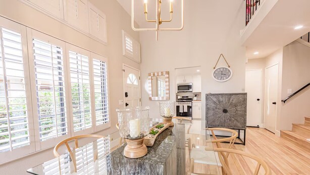 Una cocina moderna con una isla de mármol, sillas de madera y una mesa de comedor.