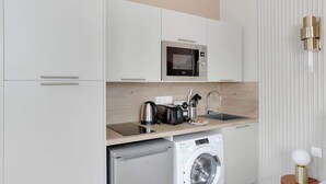 Uma cozinha compacta equipada com micro-ondas, torradeira, chaleira e máquina de lavar.