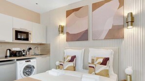 Quarto de hotel com cama, máquina de lavar, micro-ondas e pia.