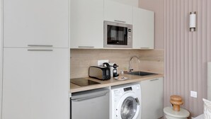 A compact kitchenette with a microwave, toaster, sink, and washing machine. - Cocon climatisé confortable – Neuilly (Neuilly-sur-Seine)