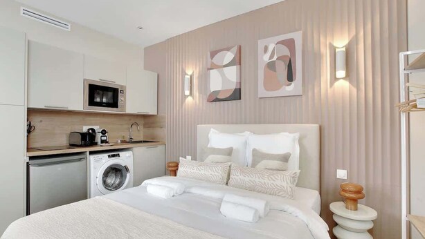 A hotel room with a bed, a washing machine, a microwave, and a sink. - Cocon climatisé confortable – Neuilly (Neuilly-sur-Seine)