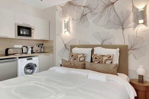 Une chambre d’hôtel équipée d’un lit, d’une machine à laver, d’un four à micro-ondes et d’un évier.